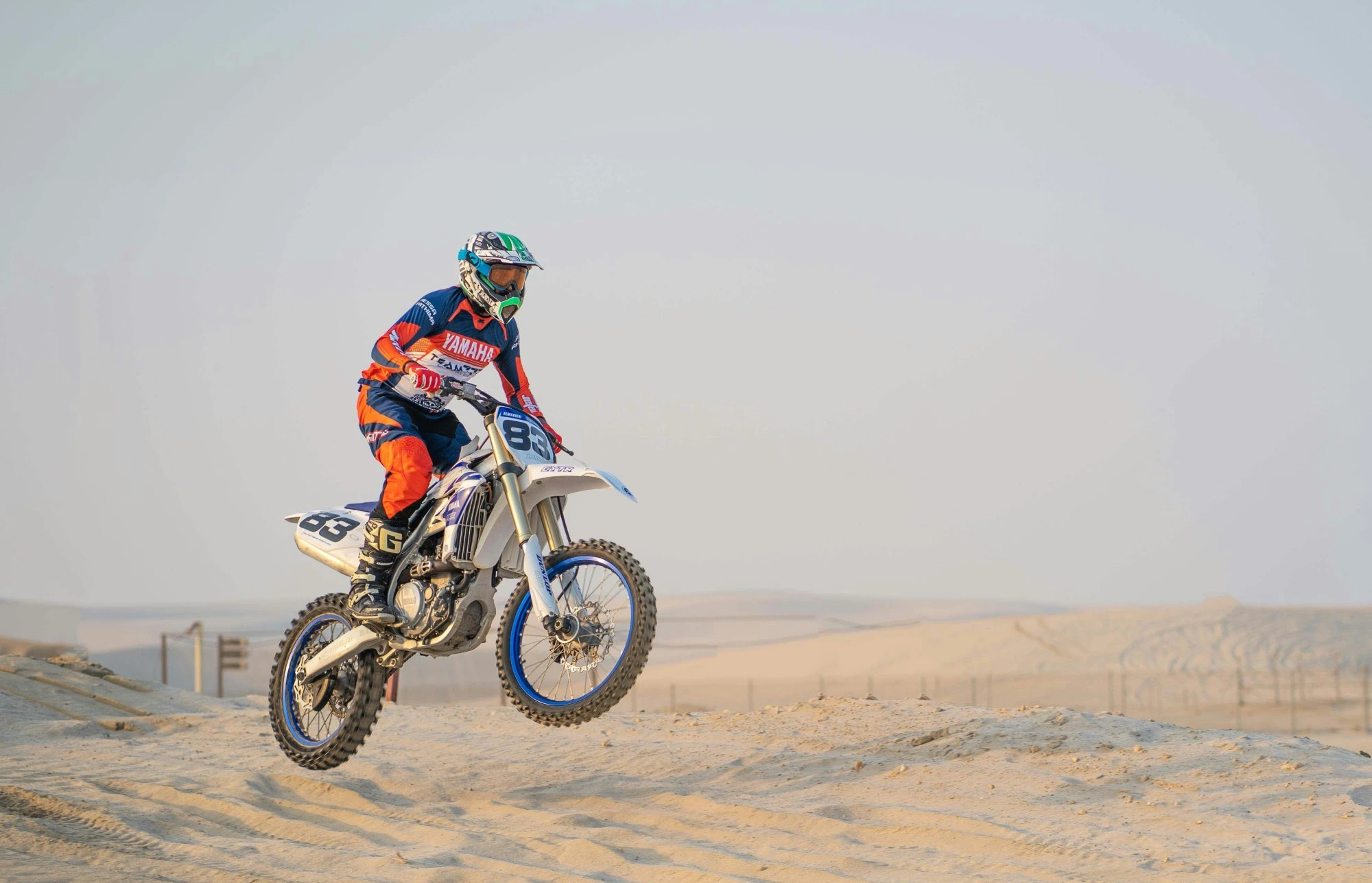 Motorbike jumping over dunes near Sealine Beach. Unsplash