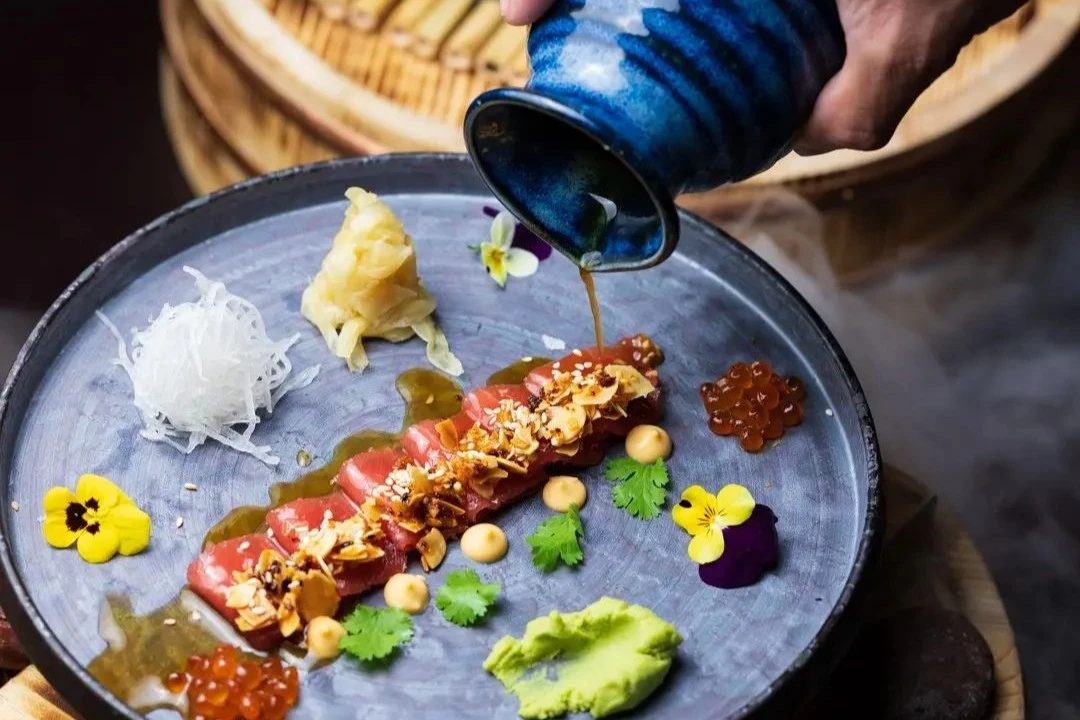 Dressing being added to a dish at Kuuru