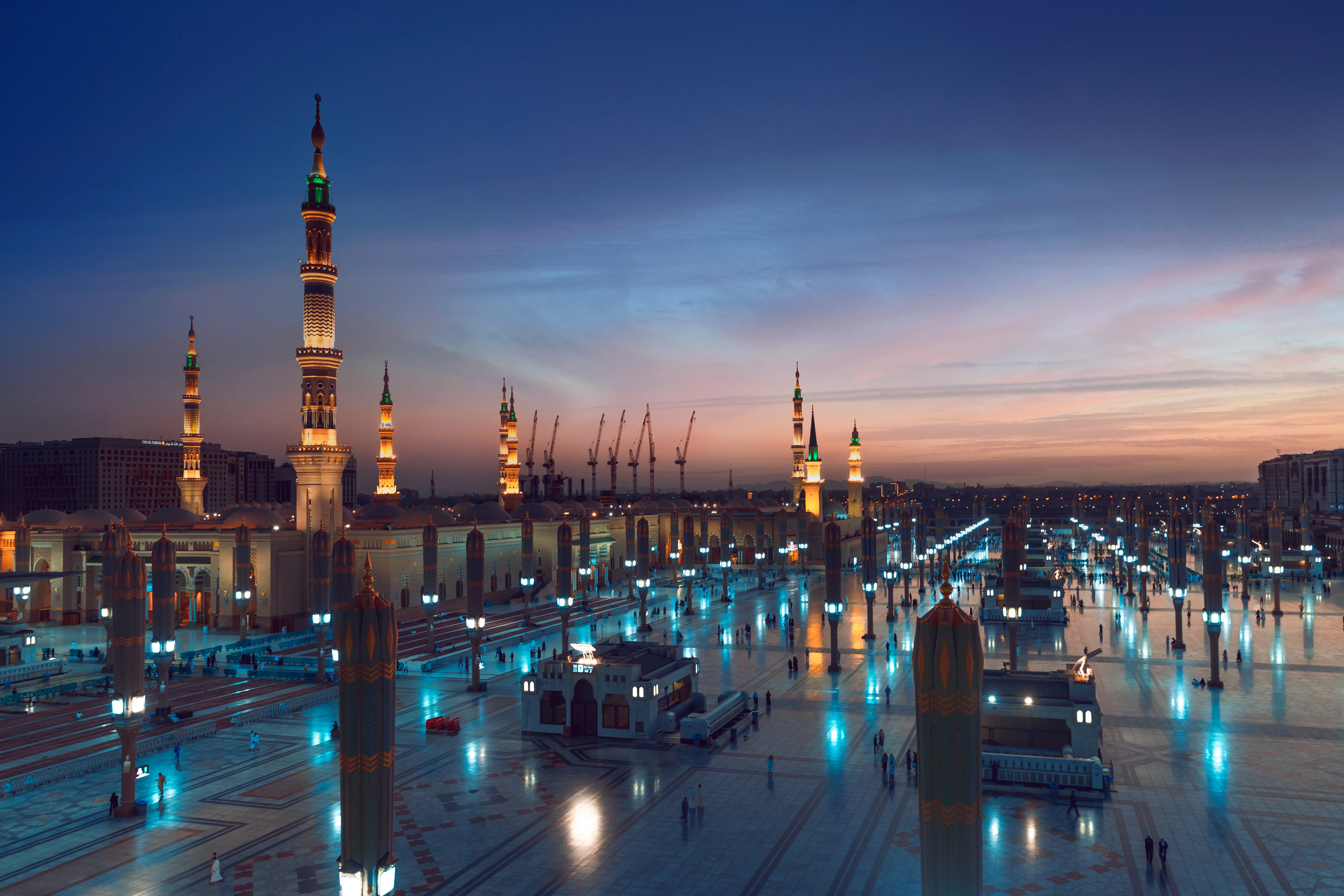 Worshippers in traditional dress walking through the courts of the Medina Haram Piazza at dusk. STA